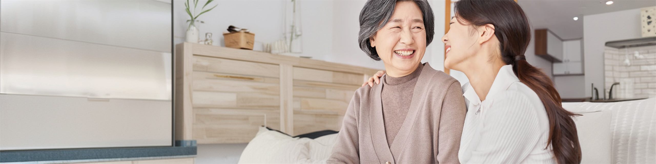 집에서 어르신과 방문간호사가 마주 보며 웃고 있다